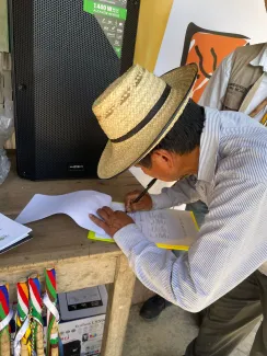 Hombre indígena firmando lista de asistencia