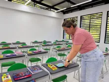 Profesora de la escuela organizando útiles escolares sobre pupitres
