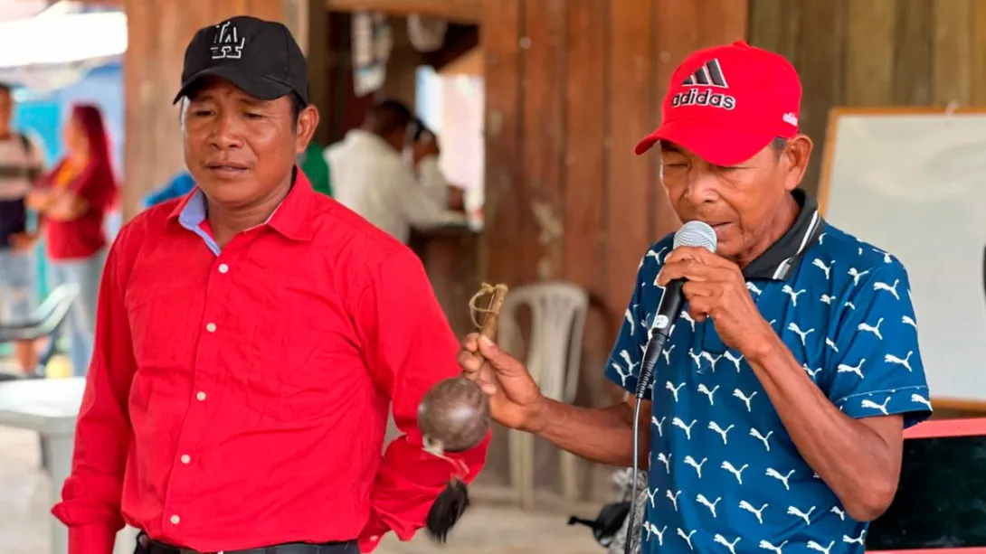 Hombres indígenas hablando por micrófono